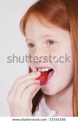 stock photo Cute redhead girl eating a strawberry
