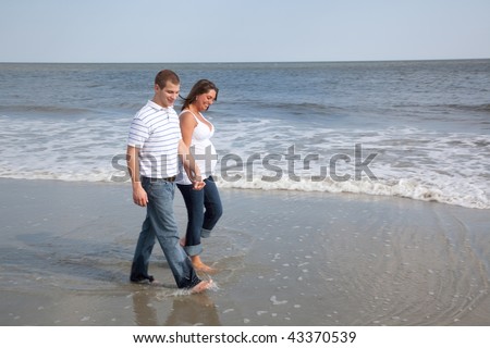 Husband and wife walk on beach holding hands