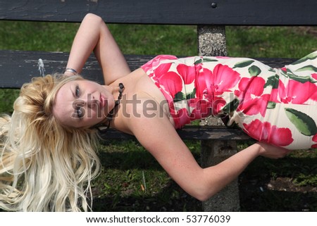 Blond woman outside laying on a bench