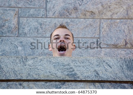 Man resting on a cut stone wall with mouth open