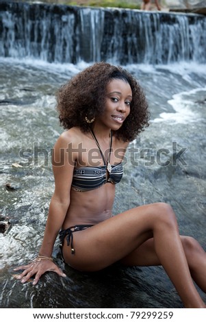 Lovely black woman outside by a stream and, in a swimsuit
