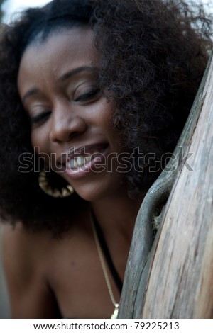 Pretty black woman laying outside on a bench, with a white flower in her hair and a smile on her face