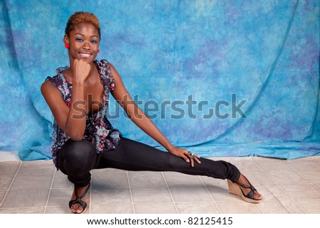 Pretty black woman squatting down on the floor with a thoughtful, and pensive expression