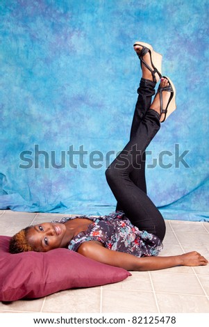 Lovely black woman laying on her back with her legs raised up in the air