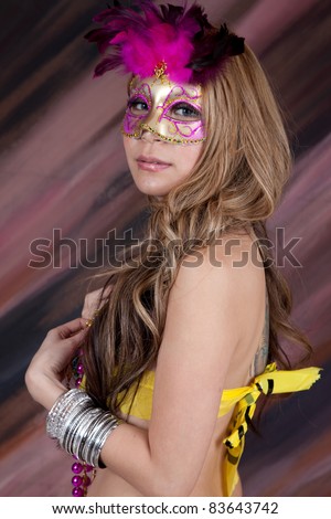 Lovely smiling woman dressed for a costume party, with  mask and hat, and  beads