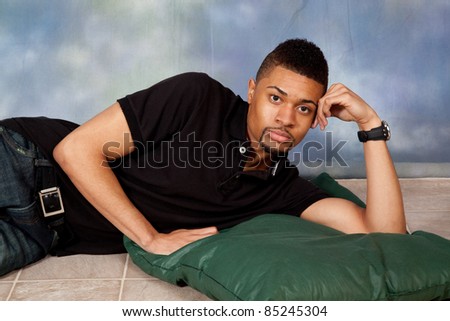 Handsome man laying down with eye contact and a pensive, thoughtful expression