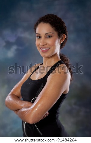 Strong, athletic woman looking at the camera with a happy smile, her arms crossed after a good, sweaty, workout
