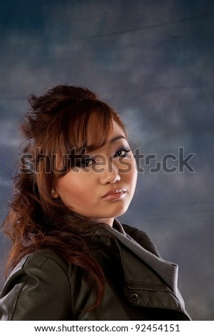 Pretty Asian woman looking over her shoulder at the camera with a friendly but serious expression