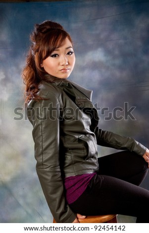 Pretty Asian woman looking over her shoulder at the camera with a friendly but serious expression