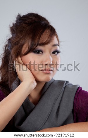 Attractive Asian American woman looking sad or thoughtful with her chin in her hand