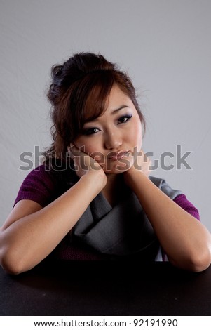 Attractive Asian American woman looking sad or thoughtful with her chin on her hand