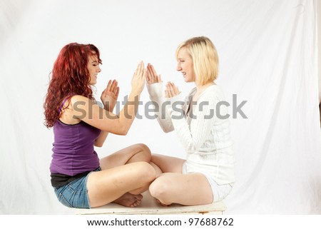Blond and redhead girls playing patty-cake for fun and entertainment