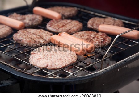 Hot dogs and hamburgers on the grill, cooking for an eat out over fire