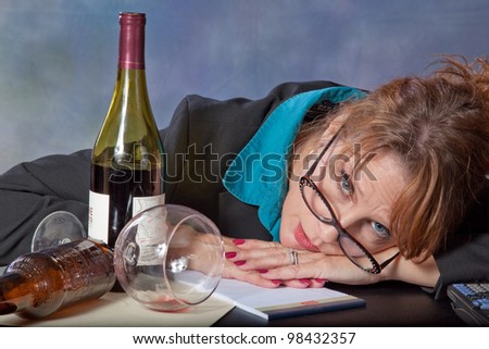 Businesswoman frustrated with accounting, paper, and money before her and her wine and beer bottles with her marking her frustration