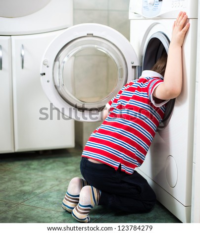 Little baby boy dangerously putting his head into washing machine - danger in bathroom