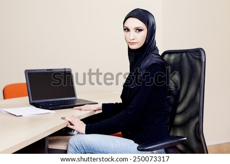 Muslim hijab wearer woman sitting at a desk with a computer at the office