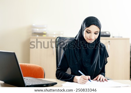 Muslim woman fills the documents while working in the office