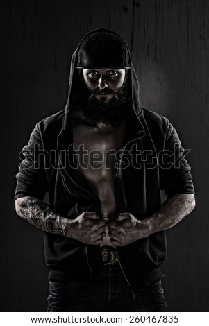 Muscular man wearing a baseball cap and black blouse on grunge wall