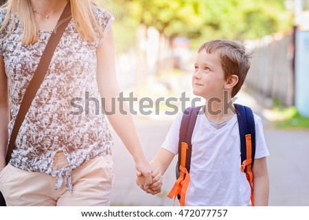 Little 7 years old boy going to school with his mother