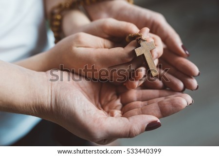 Family prayer. Mother and child hands with wooden rosary