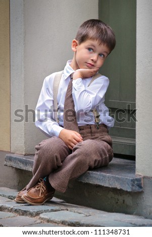 Portrait of a cute little boy sitting on the porch, facial expression series