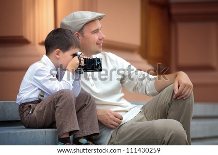 Father and little son holding retro camera in city