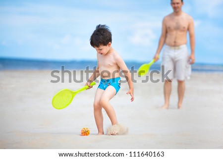 Father and son playing tennis on the beach