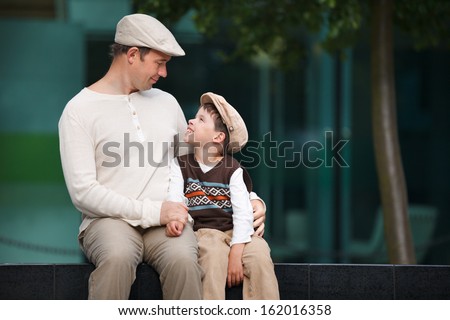 Happy Father And Son Talking And Having Rest Outdoors In City On Beautiful Summer Day