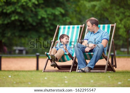 Happy father and son having rest in city park on beautiful summer day