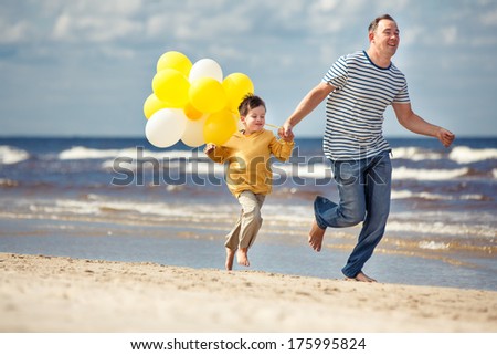 Family with yellow balloons playing on the beach