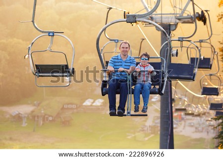 Happy father and her little son ride chair lift in Sigulda, Latvia, Europe