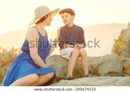 Loving mother and son talking outdoors on sunset during their summer vacation