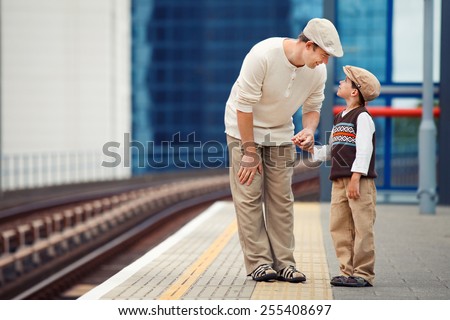 Young father and son waiting for train on railway station platform