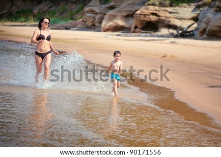 Mother and her little son running at the beach