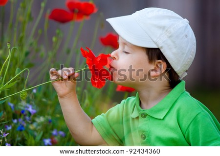 Cute little boy smells a wild flower