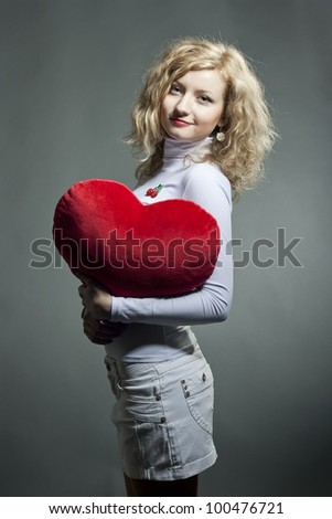 Beautiful young blond woman holding big heart.
