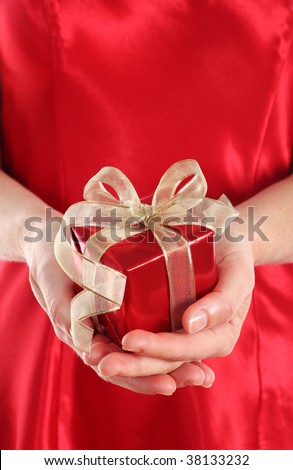 Woman in red dress holding a small red gift box with gold ribbon