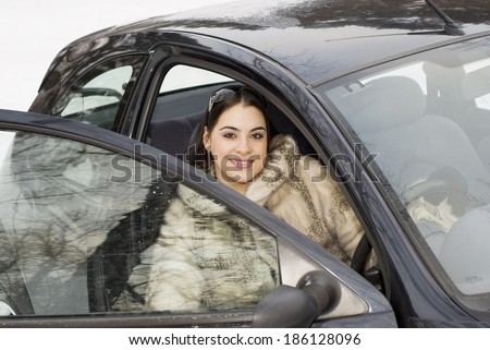 The girl in a fur coat sitting in the car