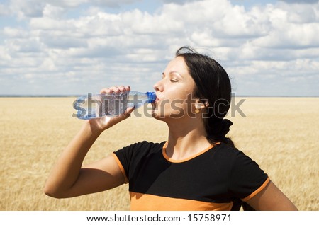 a young beautiful girl drinking water over sky background
