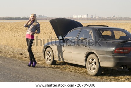 young woman talking on a cell phone, trying to get help with her broken car
