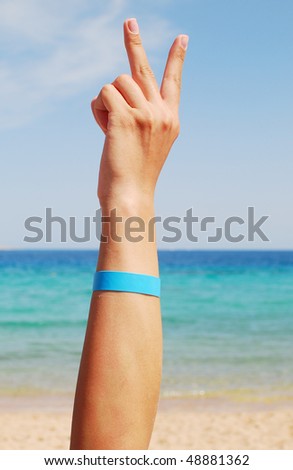 hand with all inclusive bracelet over sea background
