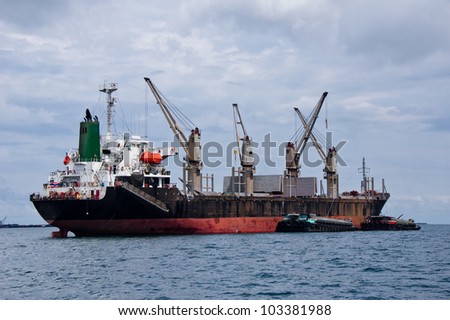 Cargo ship with small boat beside waiting to transfer things