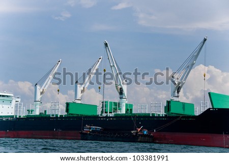 Cargo ship with small boat beside waiting to transfer things