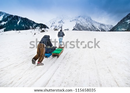 SONAMARG,INDIA-APRIL 12:Sled driver carry the tourist on snow sled up to the hill before ride down on April 12,2012 in Sonamarg, Kashmir-India.Snow sled is very popular activity at Sonamarg in winter.
