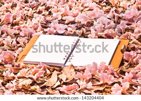 Empty note book with brown leather cover on pink flower bed.