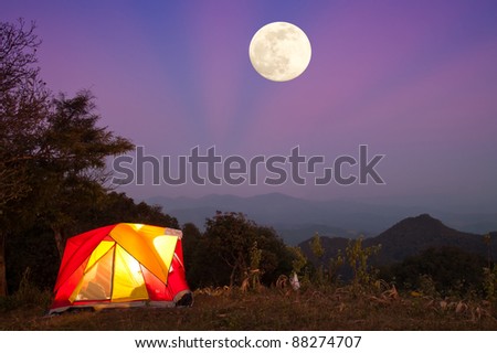 Glowing tent at night with big Moon