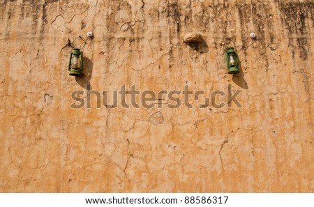 Green oil lamp hanging against ancient wall
