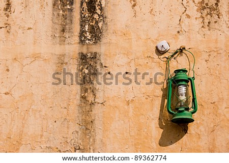 Closeup Green oil lamp hanging against ancient wall