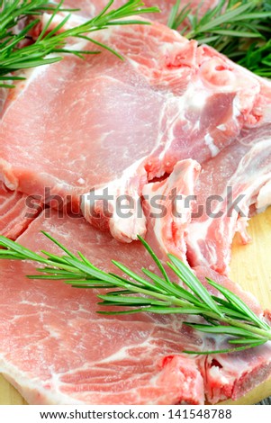 pork chops with fresh rosemary on the wooden cutting board