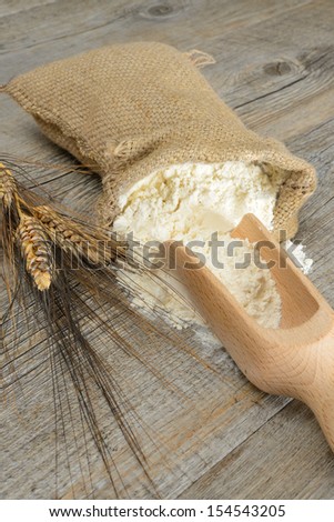 Wooden table with a sack of flour and spoon with ears
